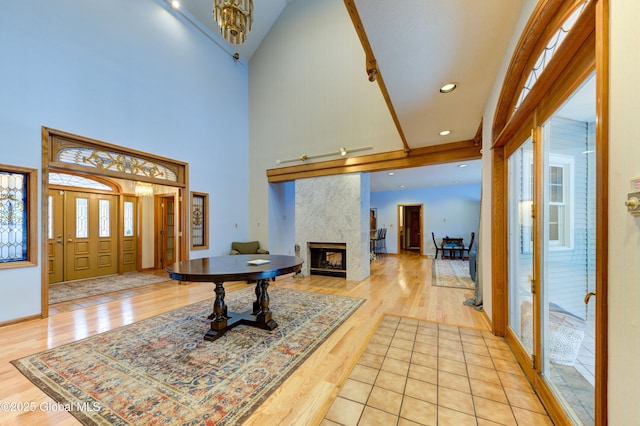 entrance foyer with a towering ceiling, a tile fireplace, light hardwood / wood-style floors, and a wealth of natural light