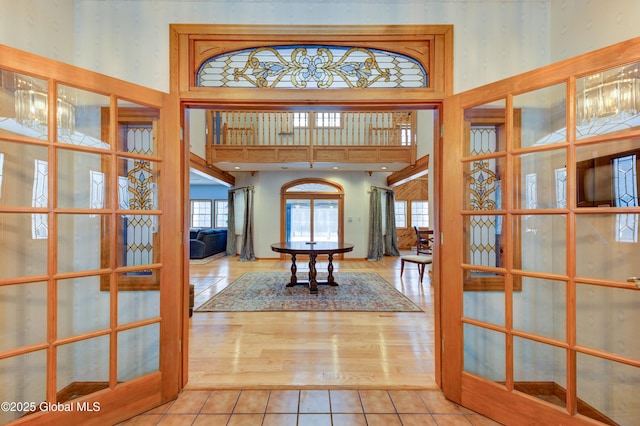 tiled foyer entrance featuring a towering ceiling, french doors, and a chandelier