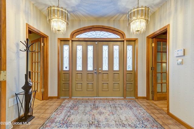 entrance foyer with french doors, light tile patterned floors, and a chandelier