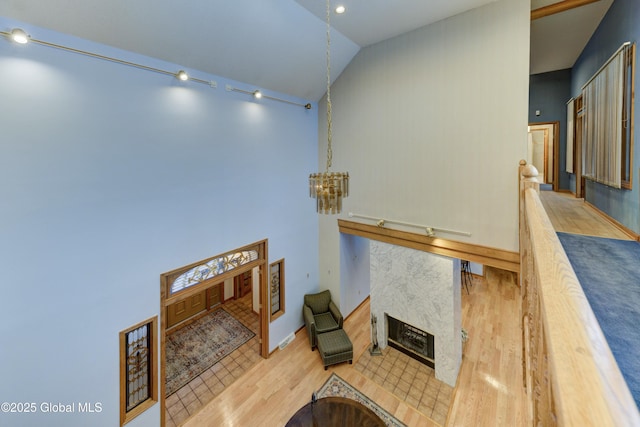 living room featuring lofted ceiling, a fireplace, light hardwood / wood-style flooring, and a chandelier