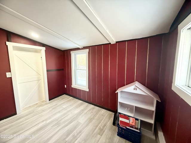 unfurnished bedroom with light wood-type flooring and beamed ceiling