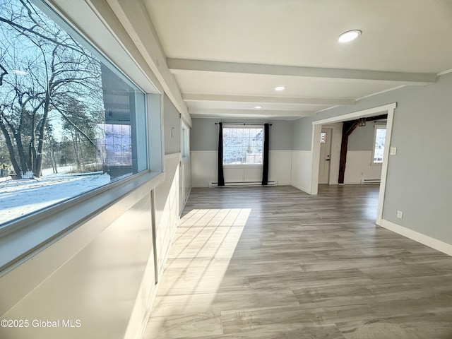 corridor with wood-type flooring, beamed ceiling, and a baseboard heating unit