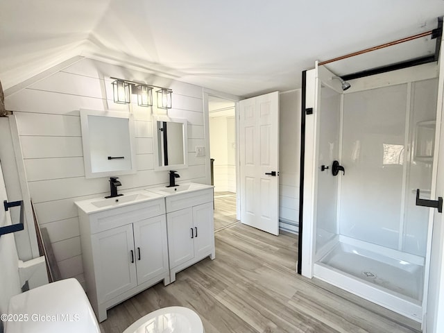 bathroom featuring hardwood / wood-style floors, toilet, wood walls, a shower, and vanity