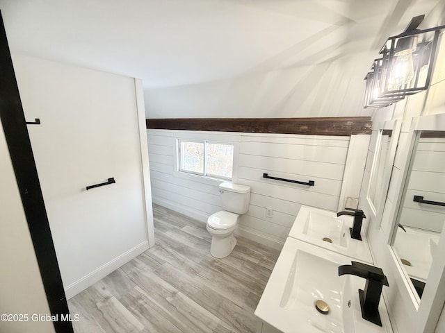 bathroom with sink, hardwood / wood-style floors, wood walls, and toilet