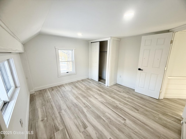 unfurnished bedroom featuring vaulted ceiling, light hardwood / wood-style floors, and a closet