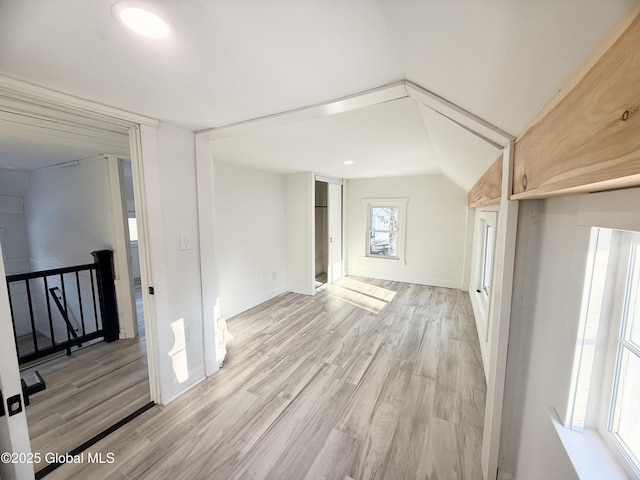 spare room featuring vaulted ceiling and light hardwood / wood-style floors