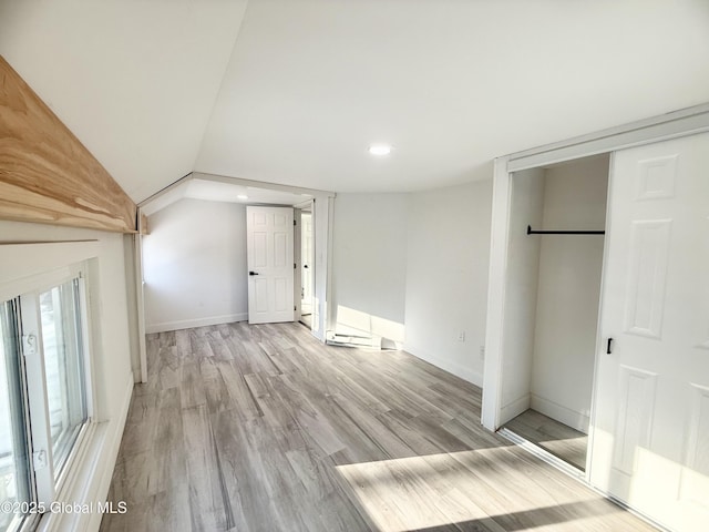 interior space featuring light wood-type flooring and vaulted ceiling