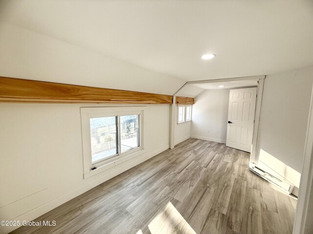 bonus room with baseboard heating, light wood-type flooring, and lofted ceiling