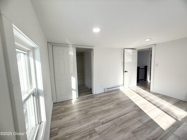 spare room with a baseboard heating unit and light wood-type flooring