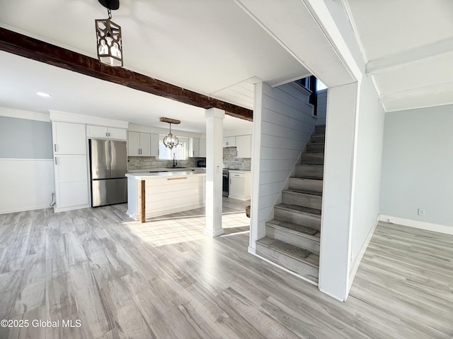 unfurnished living room with beam ceiling, light hardwood / wood-style flooring, and sink