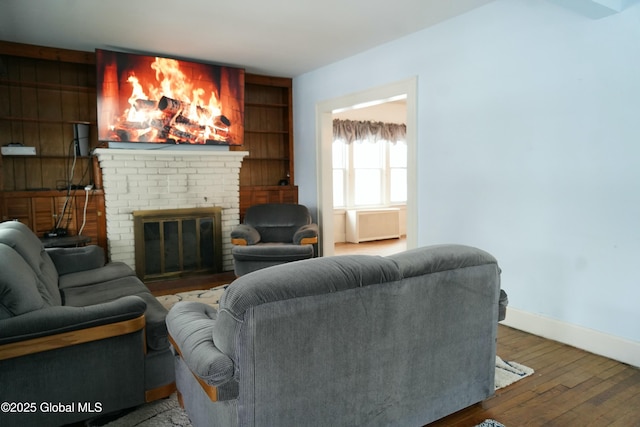 living room with wood-type flooring, built in shelves, and a fireplace