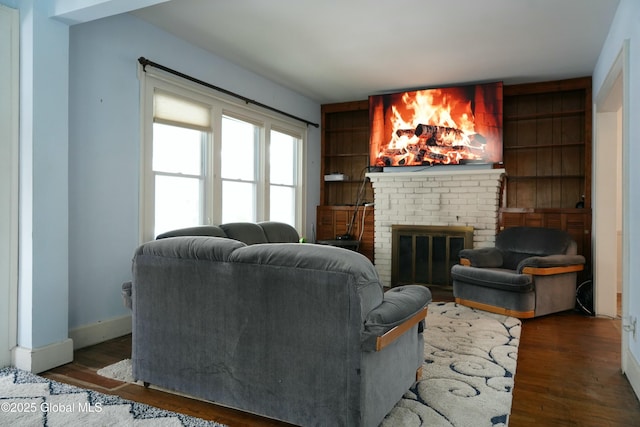 living room with a fireplace, built in features, and dark hardwood / wood-style floors