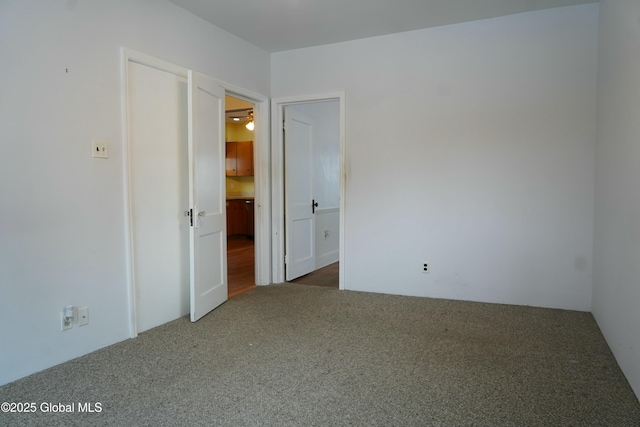 empty room featuring ceiling fan and dark colored carpet