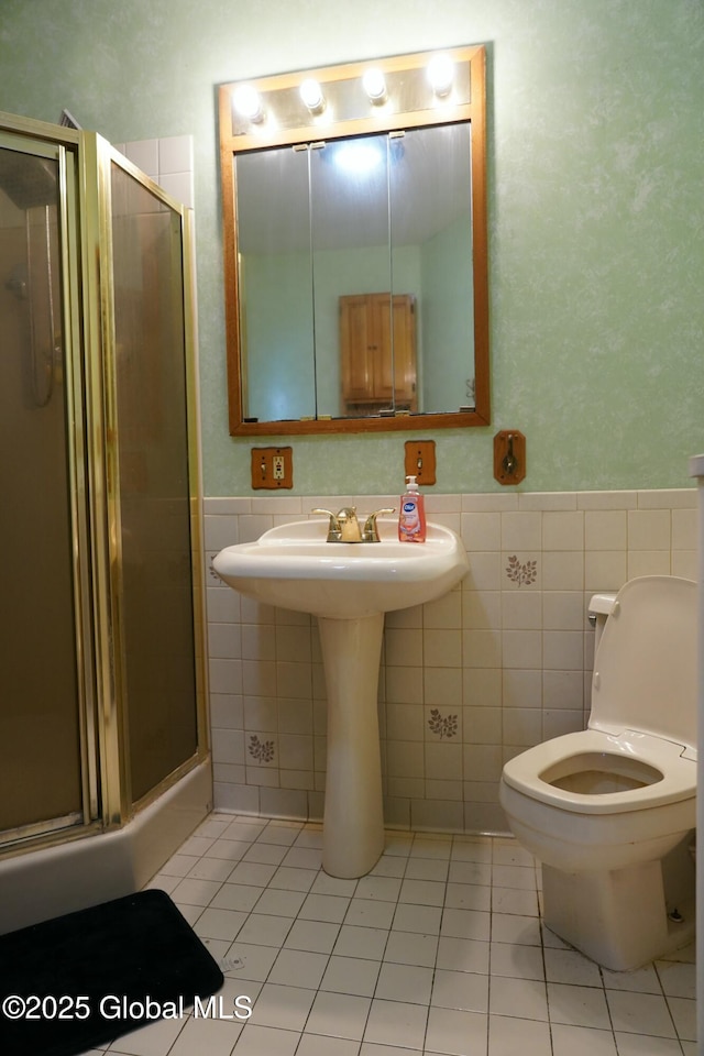 bathroom with tile walls, toilet, an enclosed shower, and tile patterned flooring