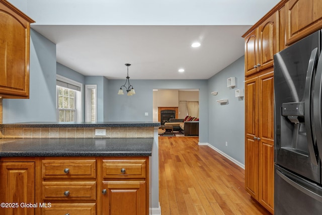 kitchen featuring light hardwood / wood-style floors, decorative light fixtures, a fireplace, fridge with ice dispenser, and a chandelier