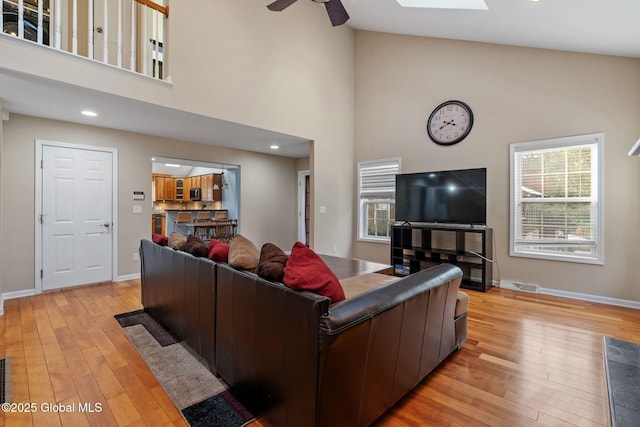 living room with high vaulted ceiling, ceiling fan, and light wood-type flooring