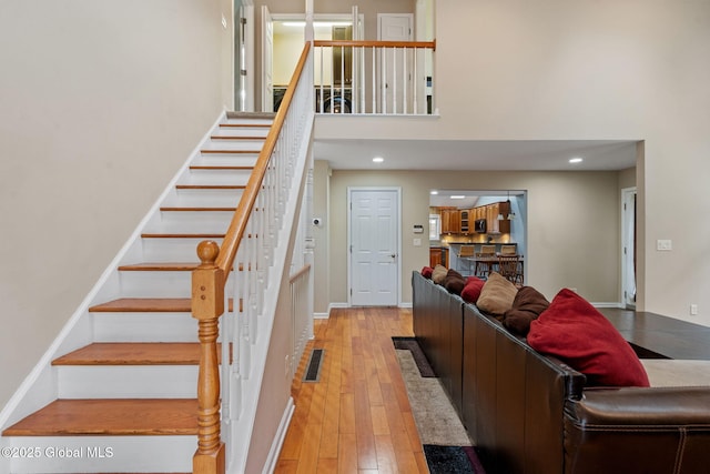 stairs featuring wood-type flooring and a towering ceiling