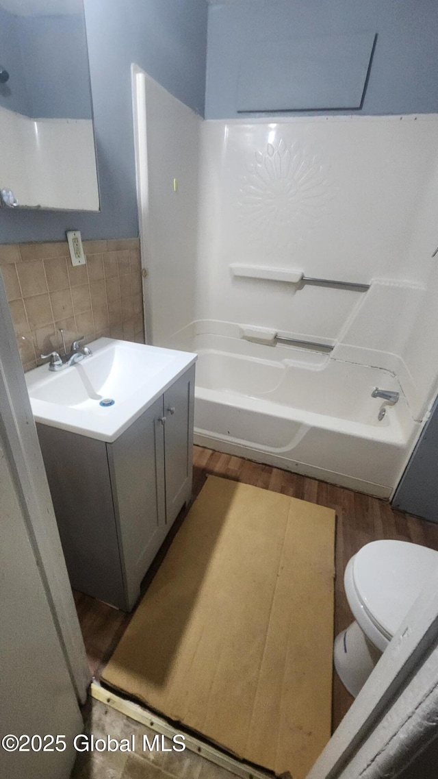 full bathroom with vanity, tasteful backsplash, toilet, hardwood / wood-style flooring, and  shower combination