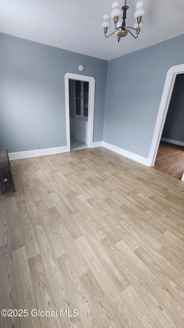 empty room featuring light hardwood / wood-style floors and a notable chandelier