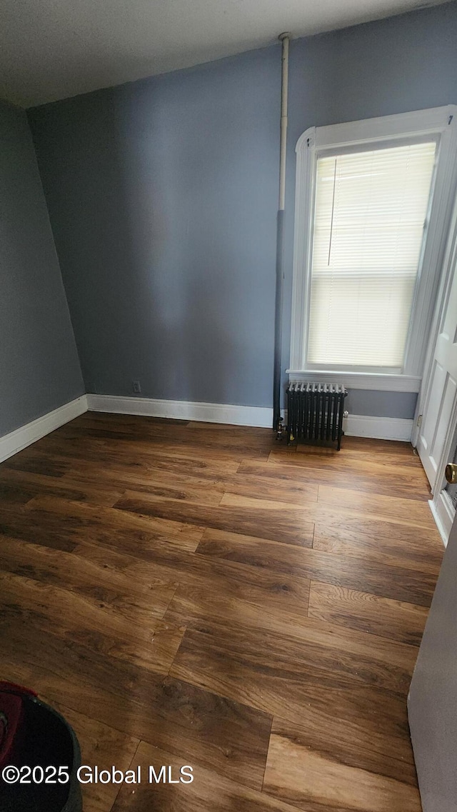 spare room featuring hardwood / wood-style flooring and radiator heating unit