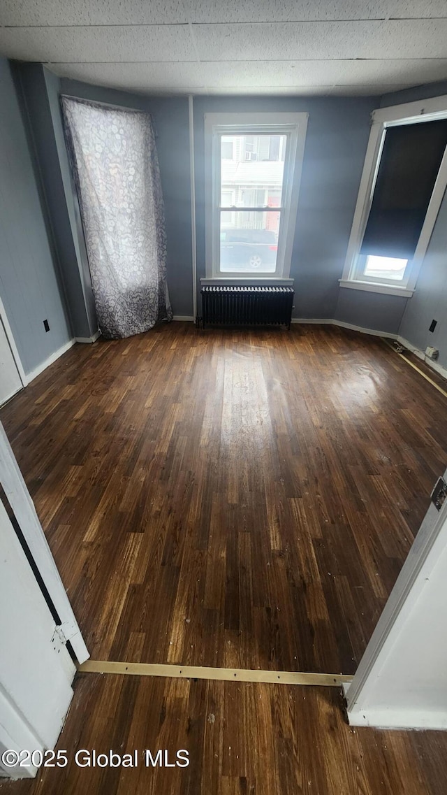 spare room featuring dark hardwood / wood-style floors and radiator