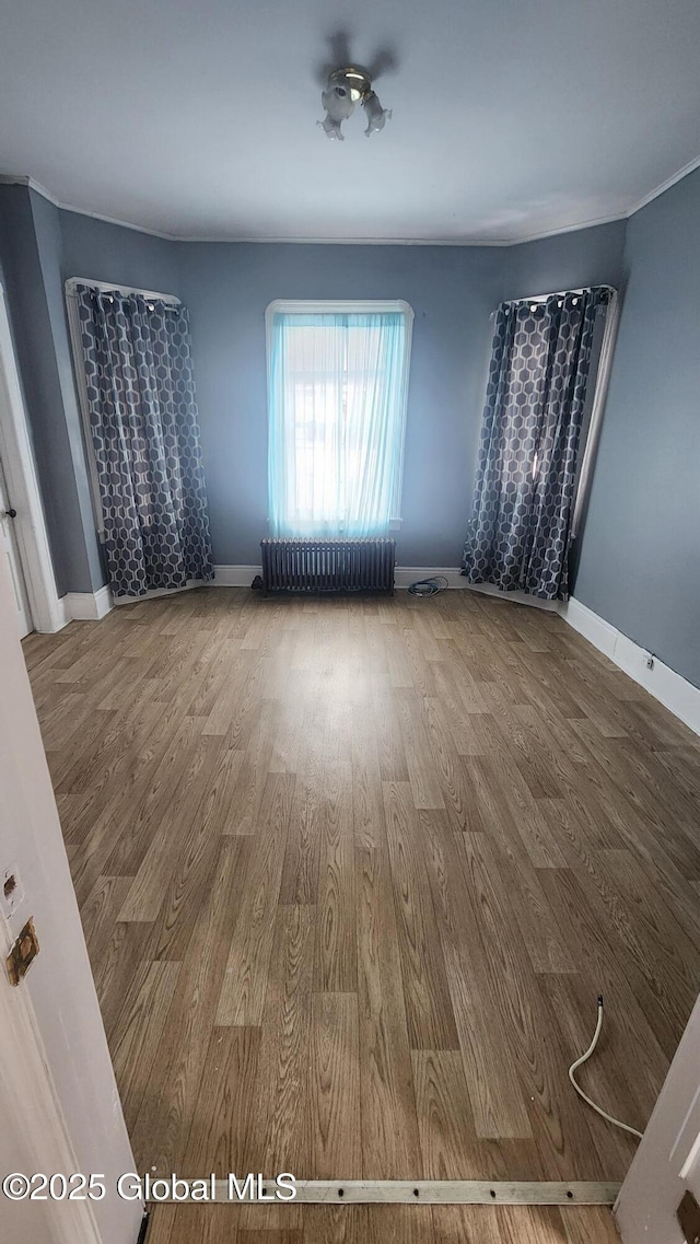 unfurnished room featuring radiator and wood-type flooring