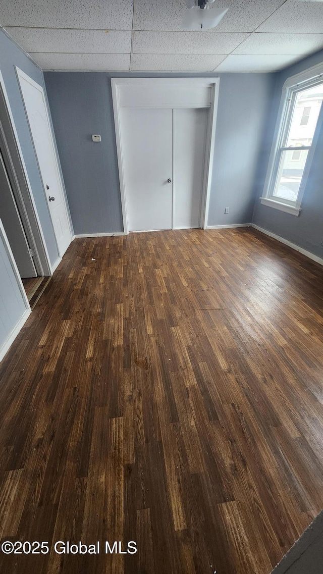 unfurnished bedroom featuring a closet, dark hardwood / wood-style floors, and a drop ceiling