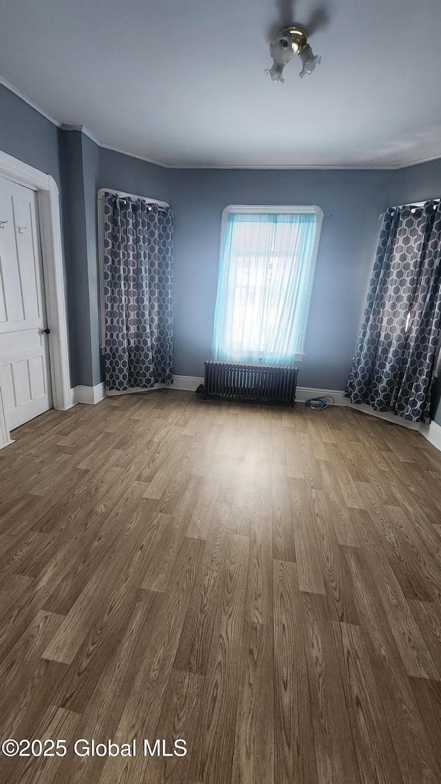 empty room with wood-type flooring and radiator