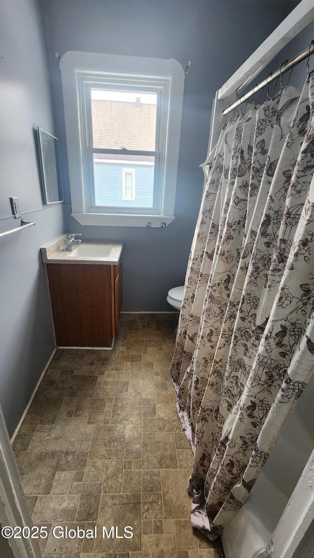 bathroom featuring toilet, vanity, and curtained shower