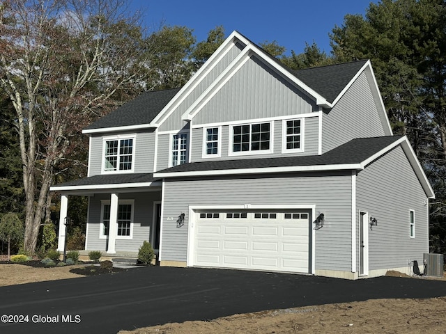 view of front of property featuring a garage, cooling unit, and covered porch