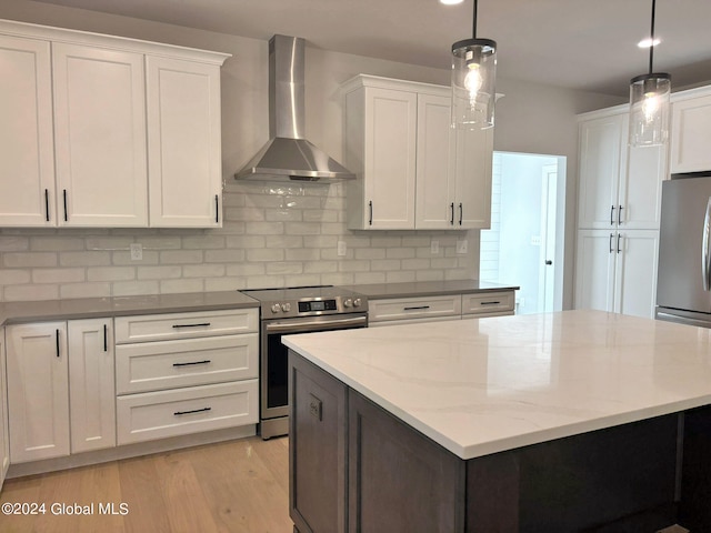 kitchen featuring white cabinetry, wall chimney range hood, stainless steel appliances, and hanging light fixtures