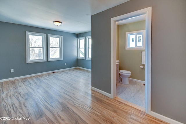 5 E Green St, Johnstown, NY 12095 - unfurnished bedroom with multiple windows, light wood-type flooring, connected bathroom, and baseboards