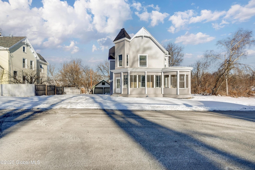 snow covered back of property featuring a sunroom