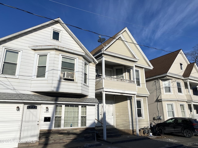 view of front facade featuring a balcony, a garage, and cooling unit