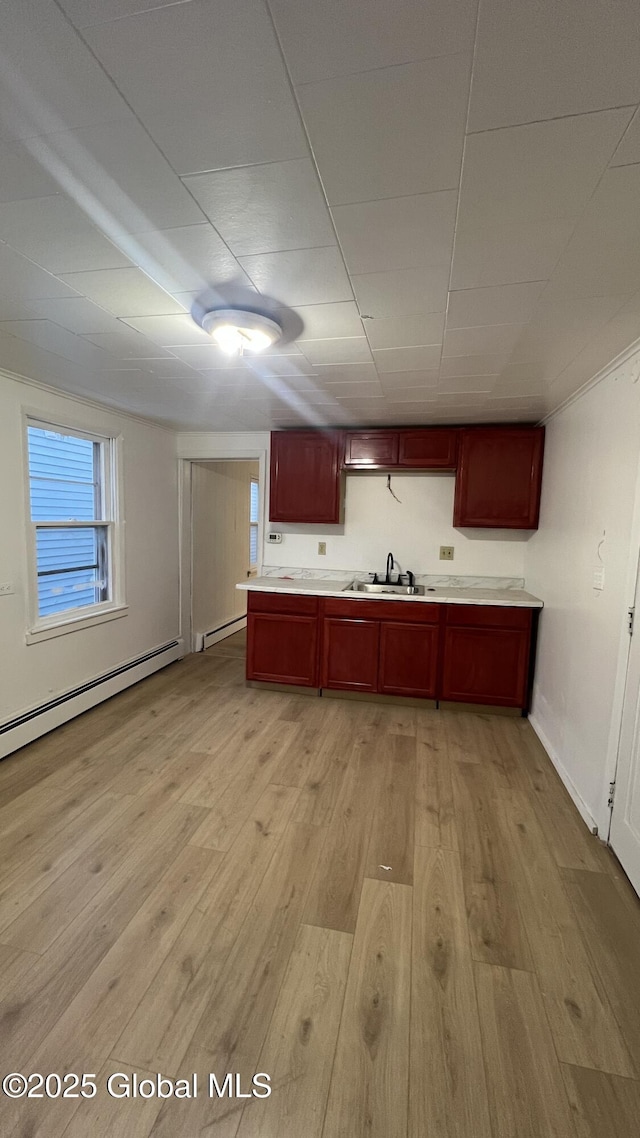 kitchen with light hardwood / wood-style floors, a baseboard radiator, and sink