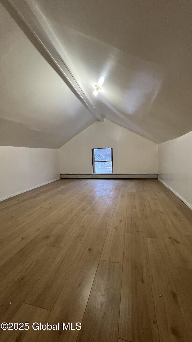 additional living space featuring wood-type flooring and vaulted ceiling with beams