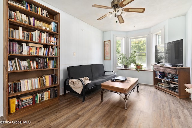 living area featuring built in shelves, ceiling fan, and hardwood / wood-style flooring