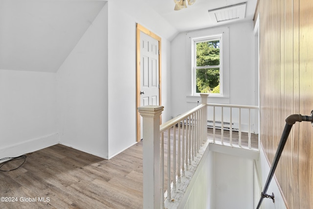 stairway with a baseboard heating unit, vaulted ceiling, and hardwood / wood-style floors