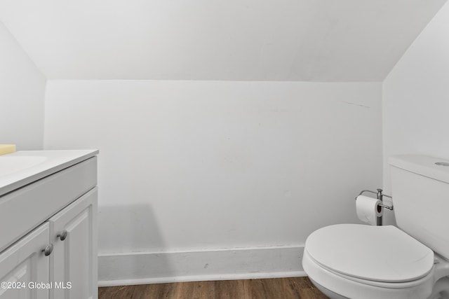 bathroom with toilet, wood-type flooring, vanity, and vaulted ceiling