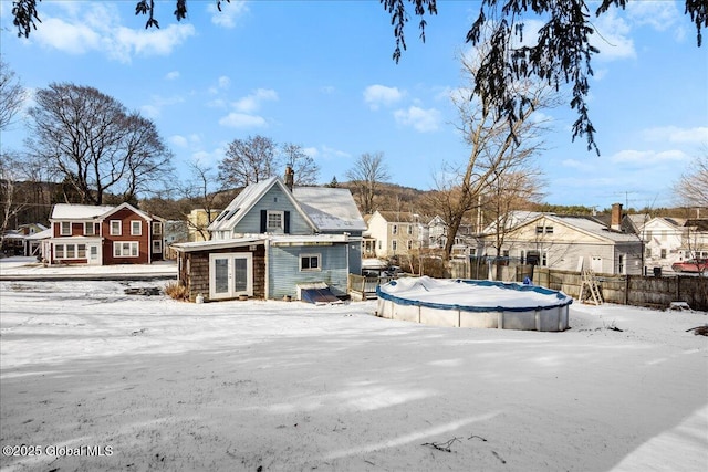 snow covered rear of property with a covered pool