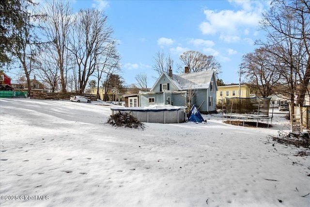 snowy yard with a trampoline and a covered pool