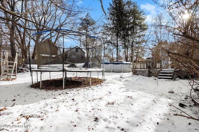 snowy yard with a trampoline and a covered pool