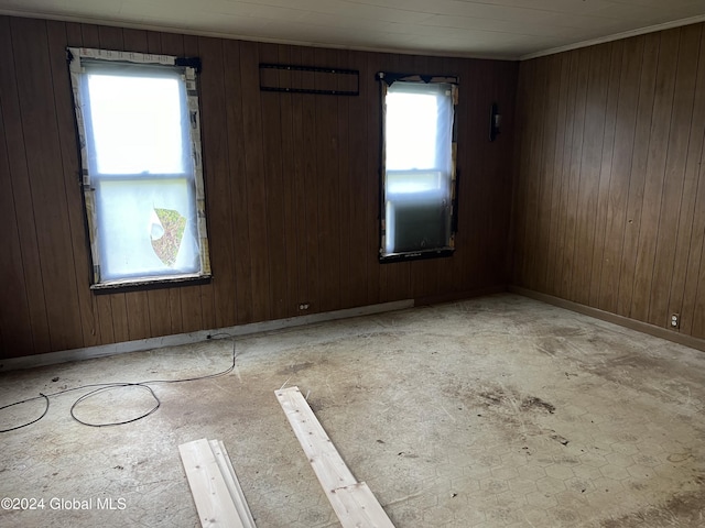 empty room featuring crown molding and wood walls