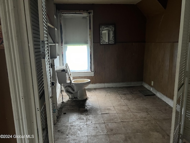 bathroom with toilet and wood walls