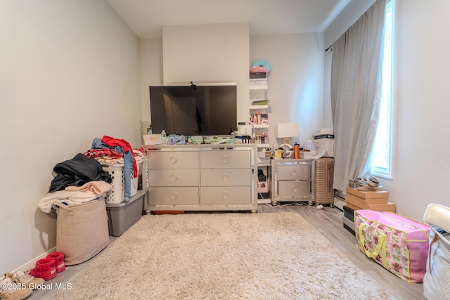 rec room with light wood-type flooring and a baseboard radiator