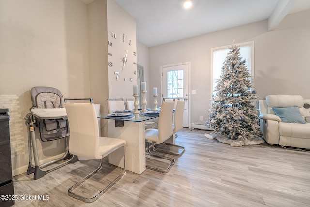 dining space with a baseboard heating unit and light hardwood / wood-style flooring