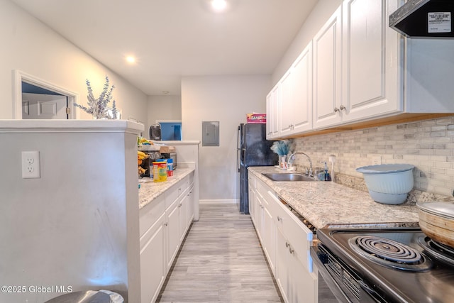 kitchen with exhaust hood, white cabinetry, electric panel, light hardwood / wood-style flooring, and sink