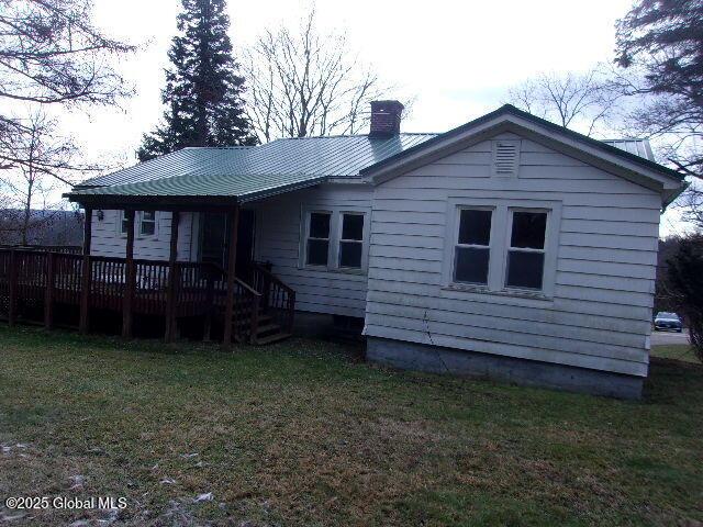 back of property featuring a yard and a wooden deck