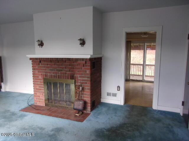 unfurnished living room featuring a brick fireplace and carpet flooring