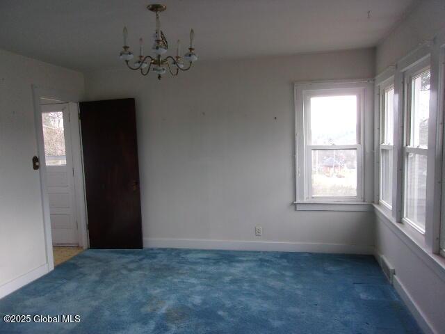 unfurnished room featuring a notable chandelier and dark carpet